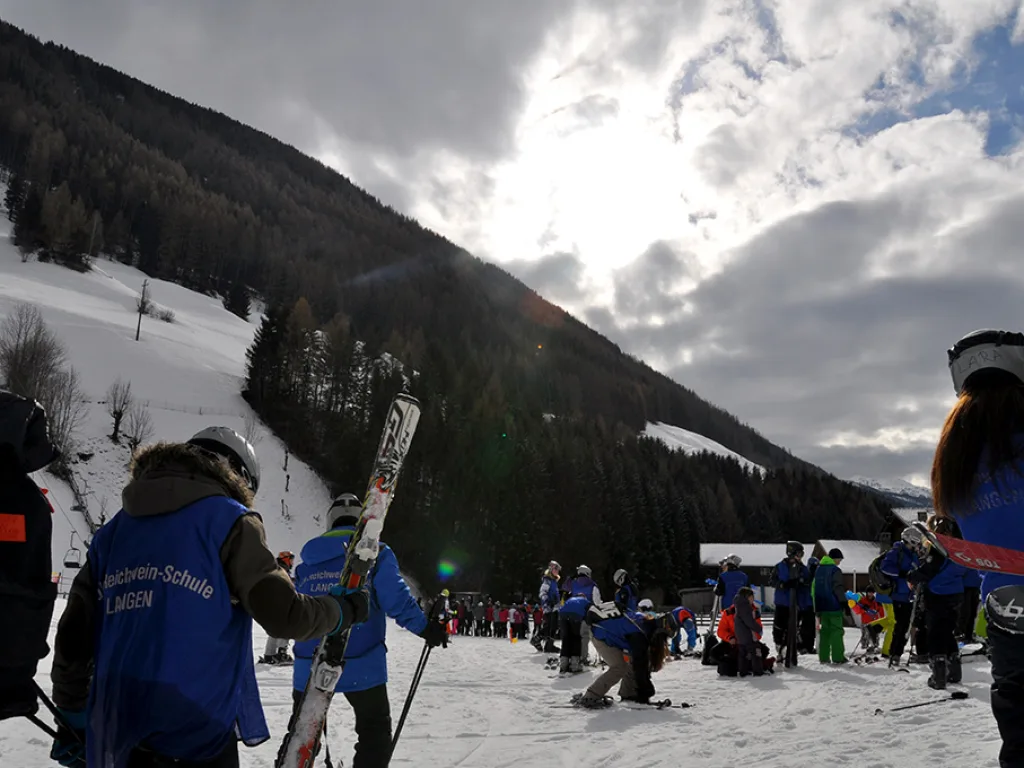 Gruppe steht im Gegenlicht am Hang, die Sonne über dem Bergrücken.